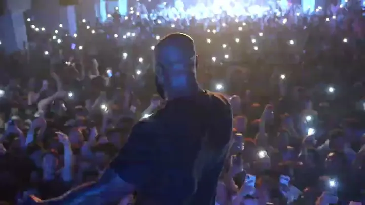 Un artiste sur scène face à une foule de téléphones allumés